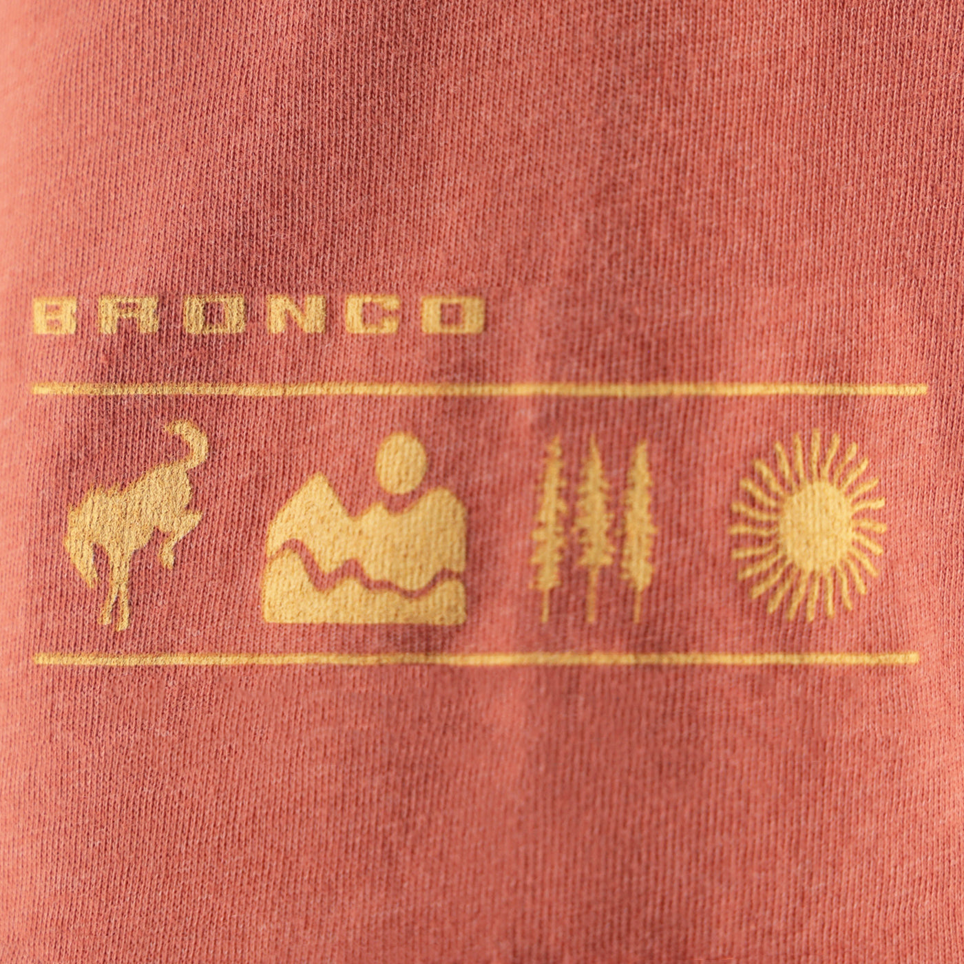 Close-up of a red fabric with 'Bronco' branding and symbols in gold.
