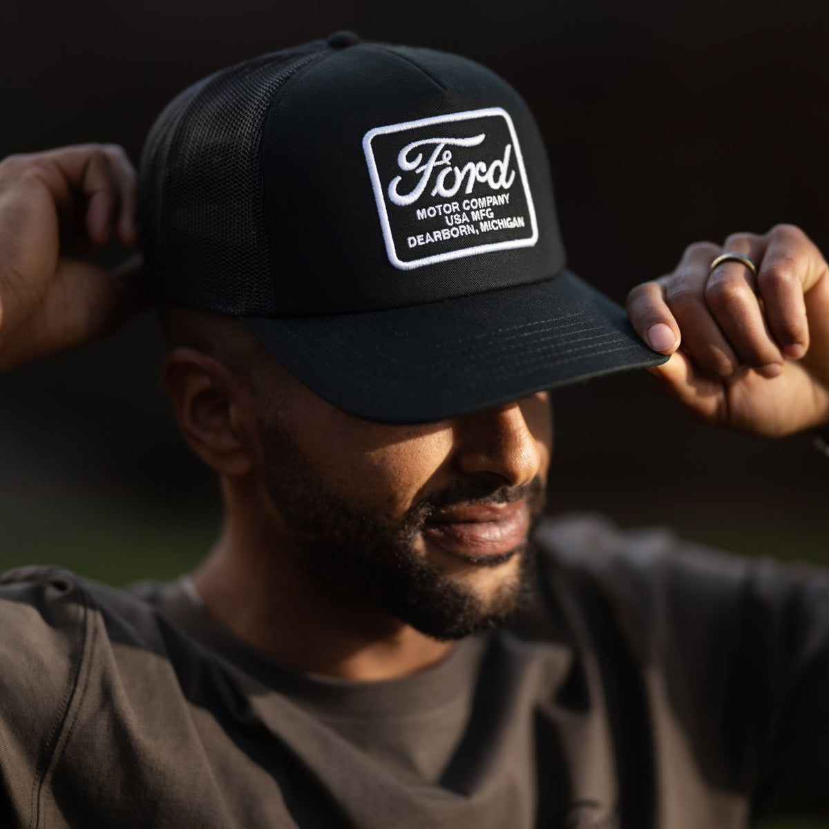 man wearing a black ford motor company patch hat 