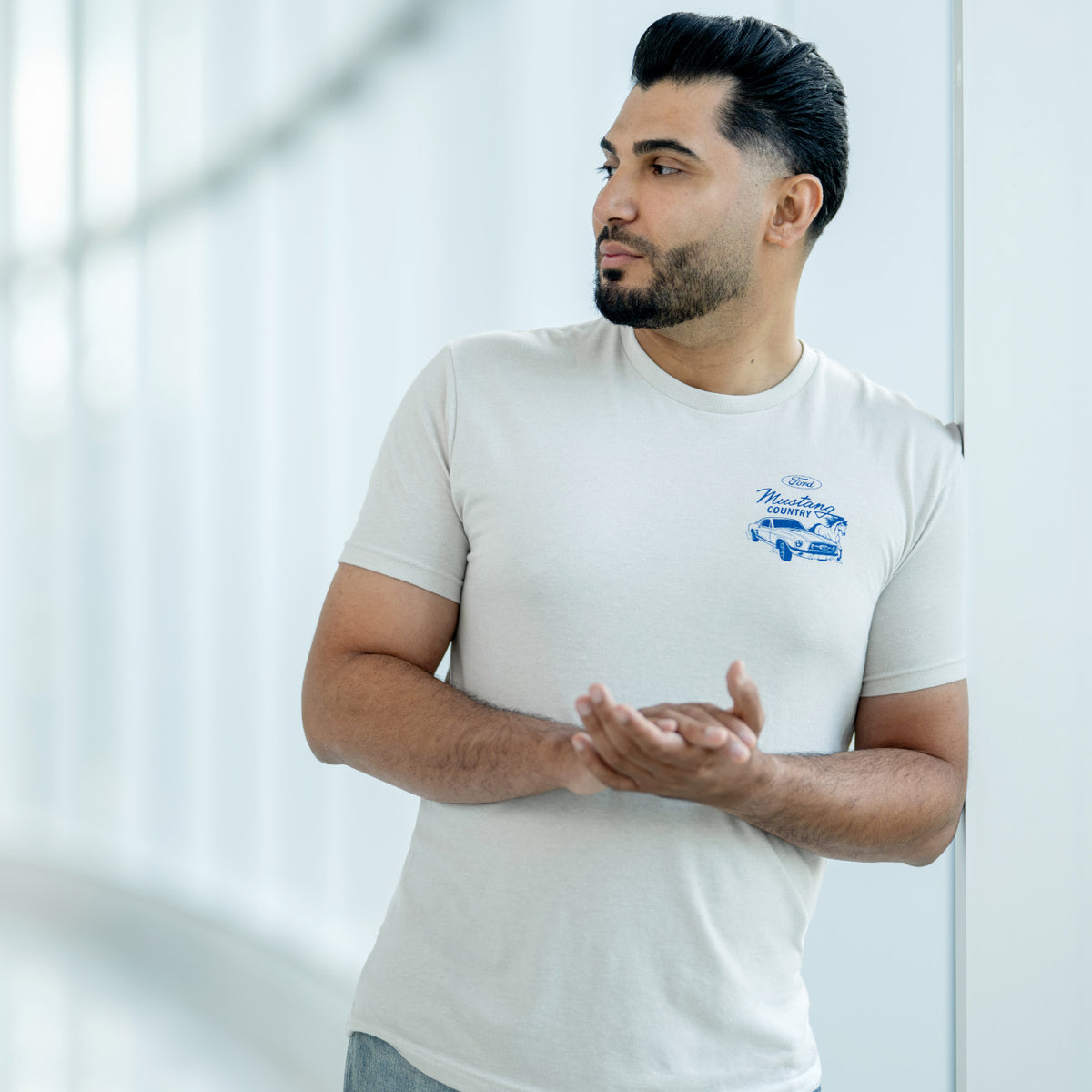 man wearing a cream Mustang country t-shirt on a white windowed background