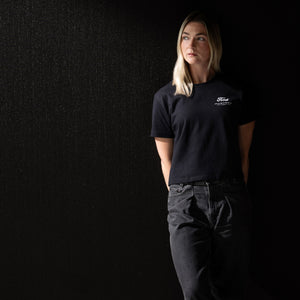 woman wearing a black Ford Mustang t-shirt in black jeans and a black background