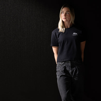 woman wearing a black Ford Mustang t-shirt in black jeans and a black background
