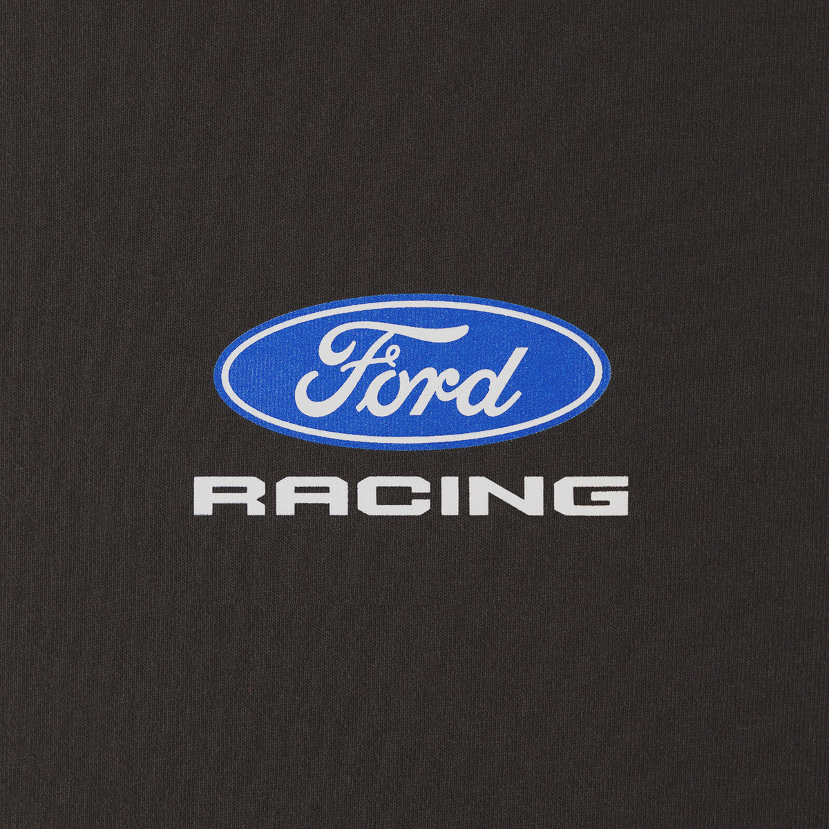 A close-up of a black fabric surface featuring a blue oval Ford logo with white script and the word 'RACING' in white below it.