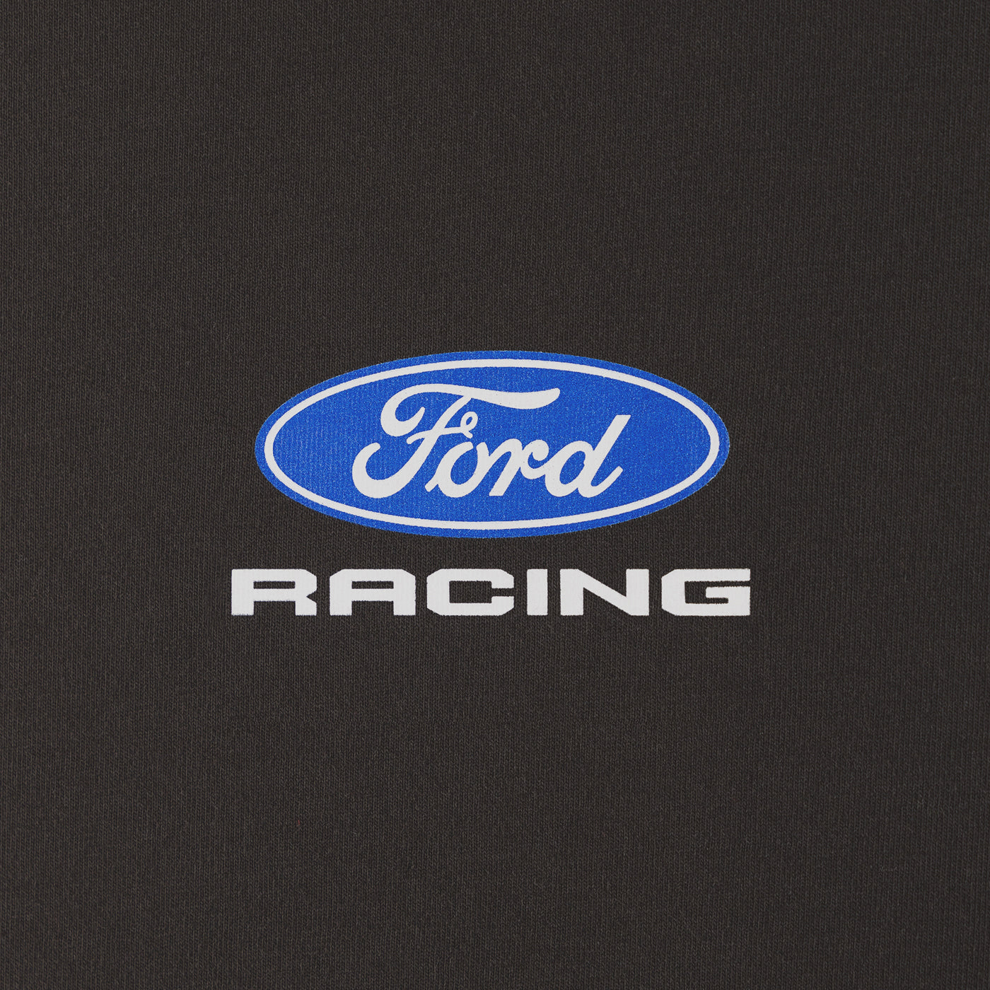 A close-up of a black fabric surface featuring a blue oval Ford logo with white script and the word 'RACING' in white below it.