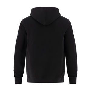 A black hooded sweatshirt shown from the back, featuring a small blue and white logo on the left sleeve, set against a plain white background.