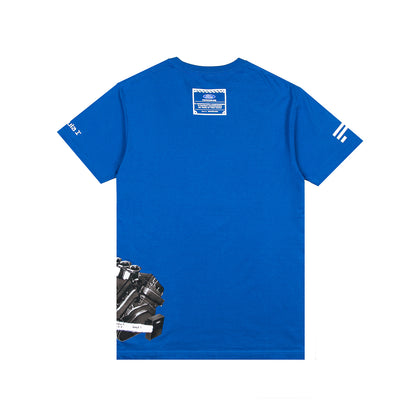 A royal blue short-sleeve t-shirt shown flat against a white background. The back of the shirt features a white rectangular patch near the collar, white graphic stripes on the sleeves, and a black and white mechanical engine illustration printed near the bottom left.
