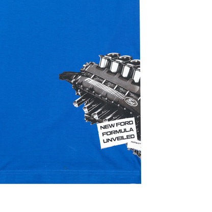 A close-up of a bright blue T-shirt with a large black-and-white engine graphic and a torn-paper style label reading 'NEW FORD FORMULA UNVEILED' on the chest.