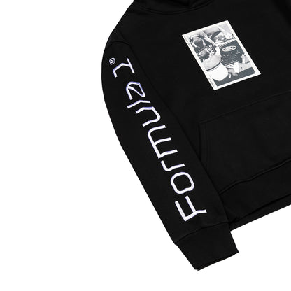 A close-up of a black hoodie featuring large white vertical 'FORTMOUTH' text printed down one sleeve and a black-and-white graphic patch on the left chest, shown on a plain white background.