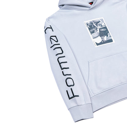 A light gray hooded sweatshirt shown on a white background, featuring a large black 'FORMULA 1' logo printed vertically down one sleeve and a rectangular black-and-white graphic patch on the left chest.