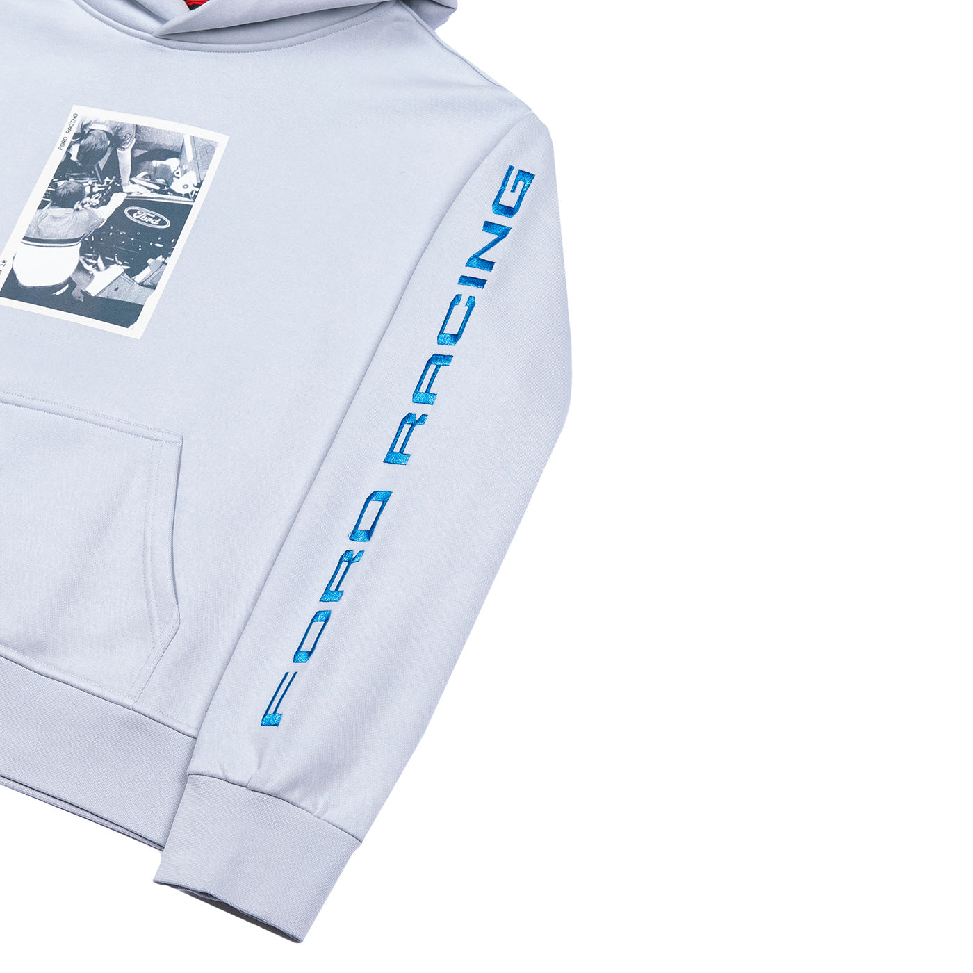 A close-up of a light gray hoodie featuring a blue vertical 'FORD RACING' logo printed down the right sleeve and a black-and-white racing graphic patch on the left chest, shown against a plain white background.