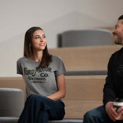 Two people sitting on a couch, one wearing a Ford Motor Co. t-shirt.