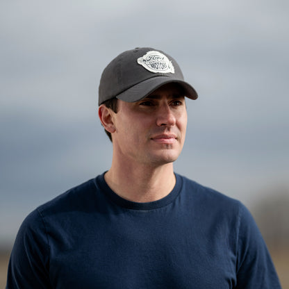 Man wearing a dark ford cap and navy shirt against a blurred background