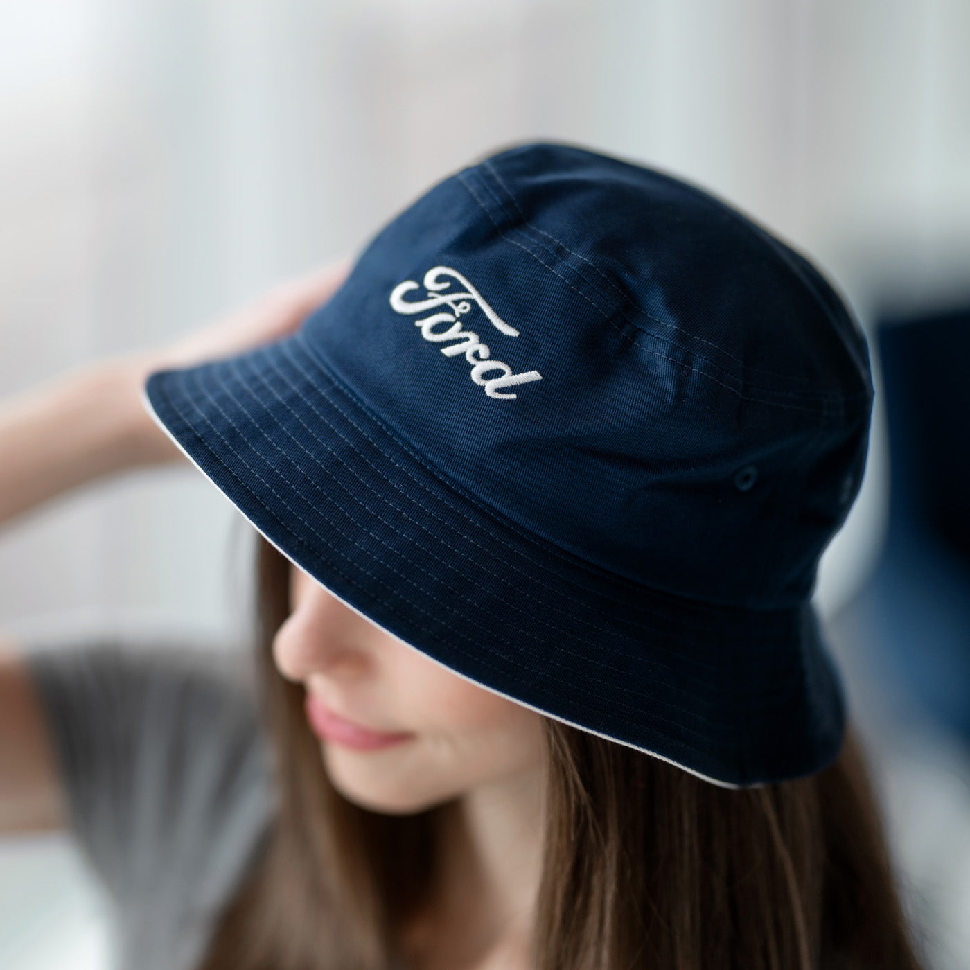 Person wearing a navy blue bucket hat with 'Ford' logo.
