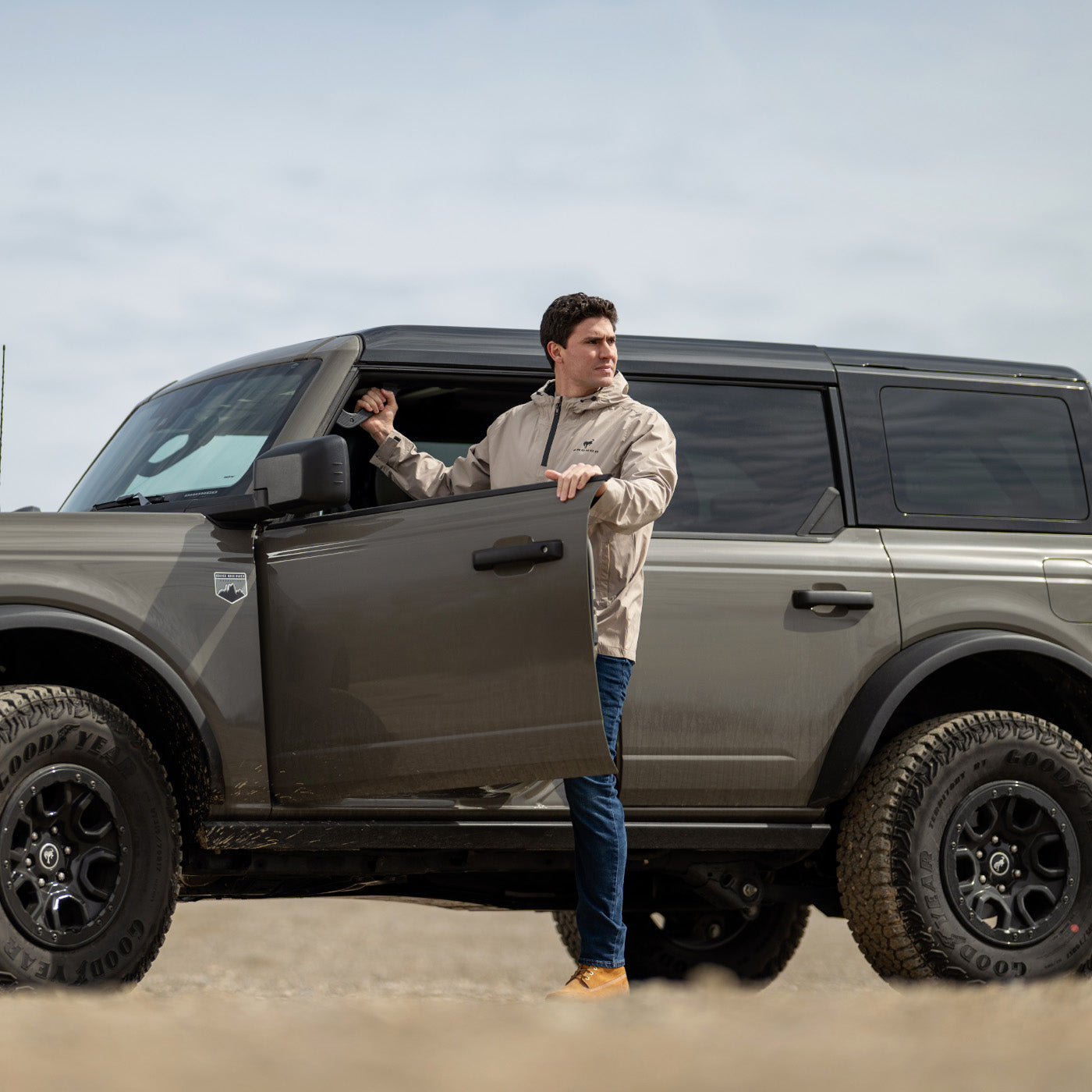 Man opening the door of a gray Bronco SUV in an outdoor setting
