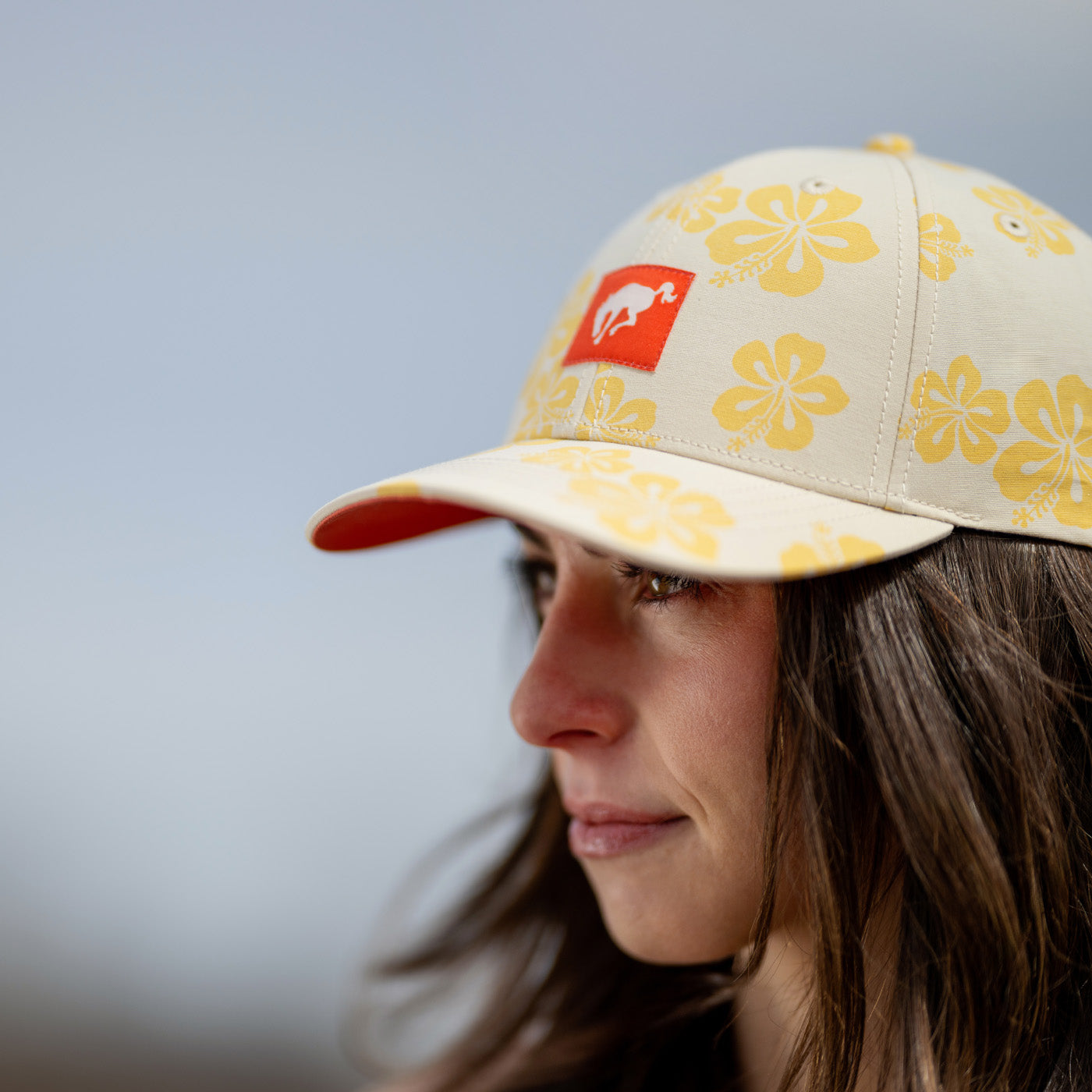 Person wearing a cap with floral patterns and a logo on a blurred background