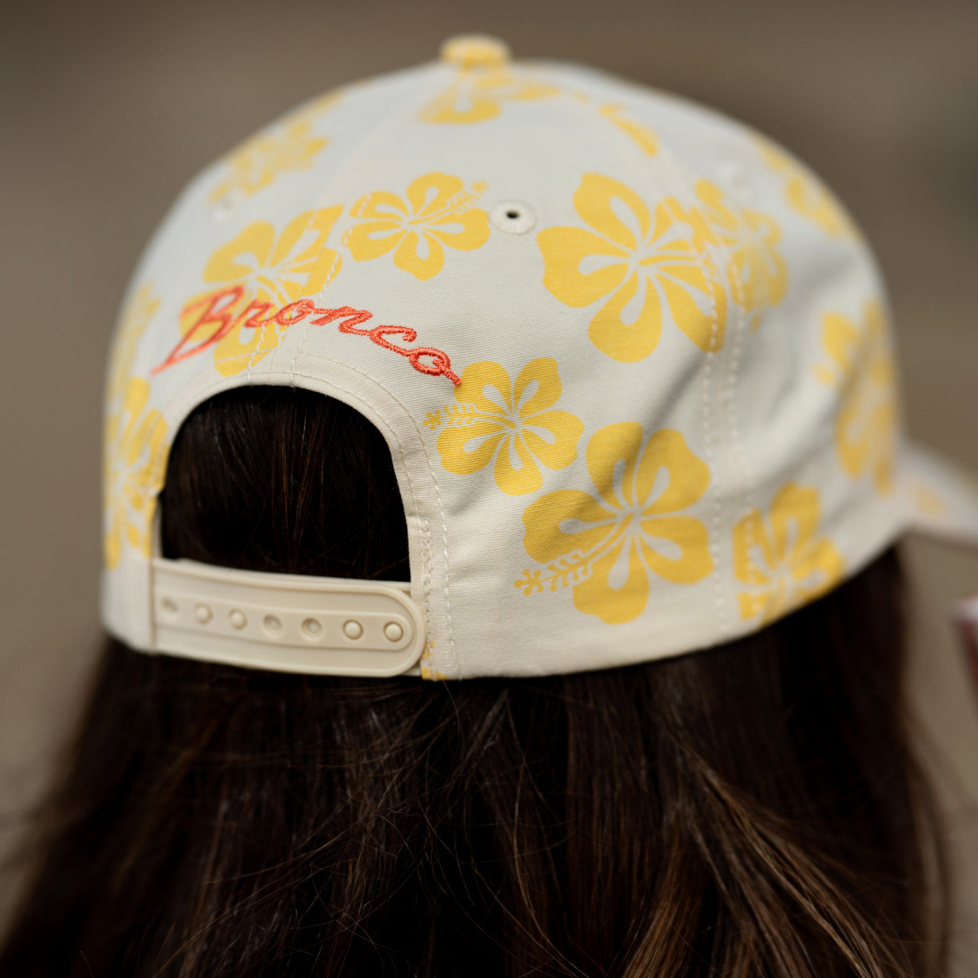 Cap with yellow floral pattern and 'Bronco' branding on a blurred background