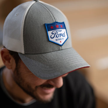 Gray cap with Ford logo hat worn by a person, blurred background
