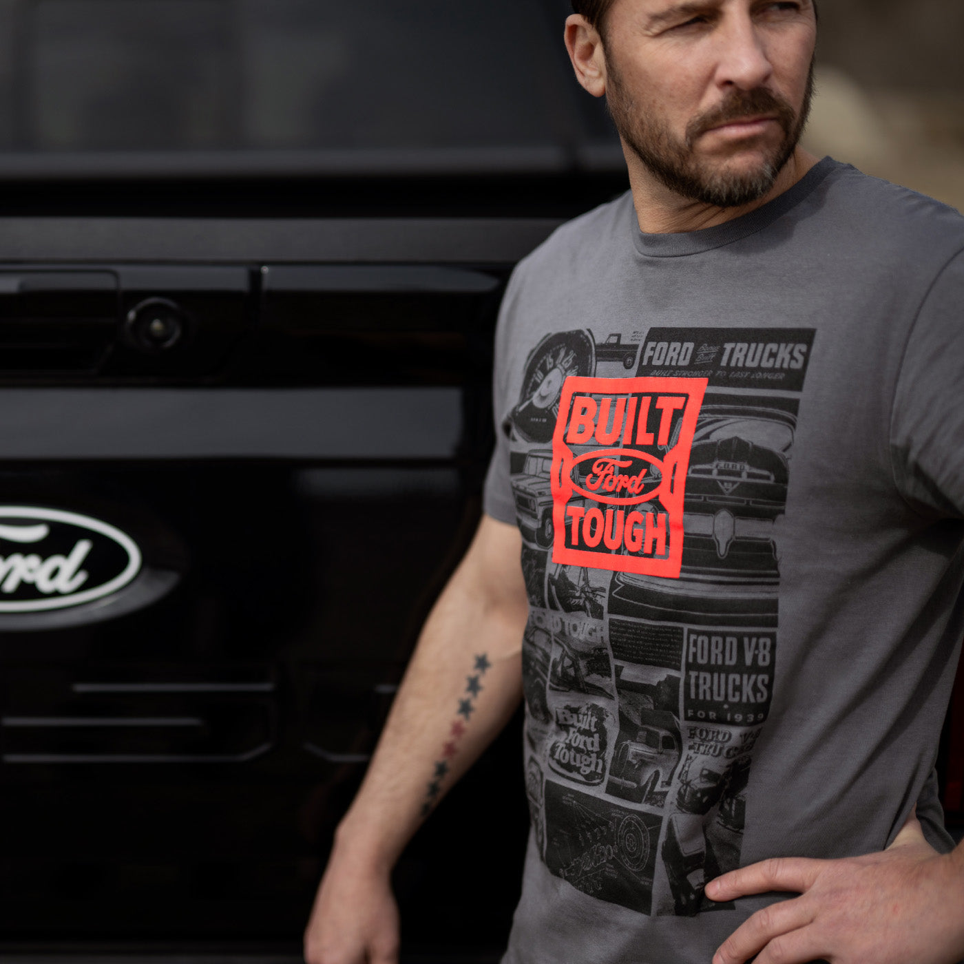 Man wearing a 'Built Ford Tough' t-shirt standing in front of a Ford truck.