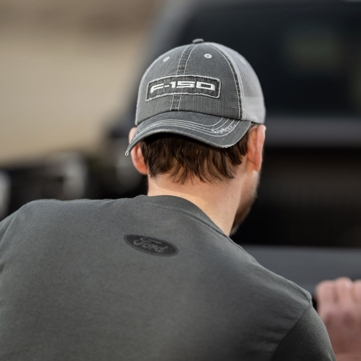 Person wearing a cap with 'F-150' logo and shirt with Ford logo, blurred background