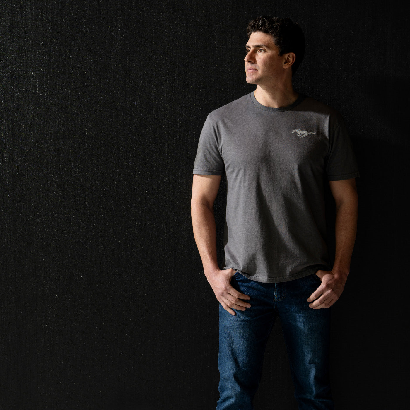 Man wearing a gray t-shirt with a Mustang logo on a black background
