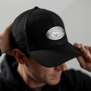 Black Mustang cap with a logo worn by a person against a neutral background