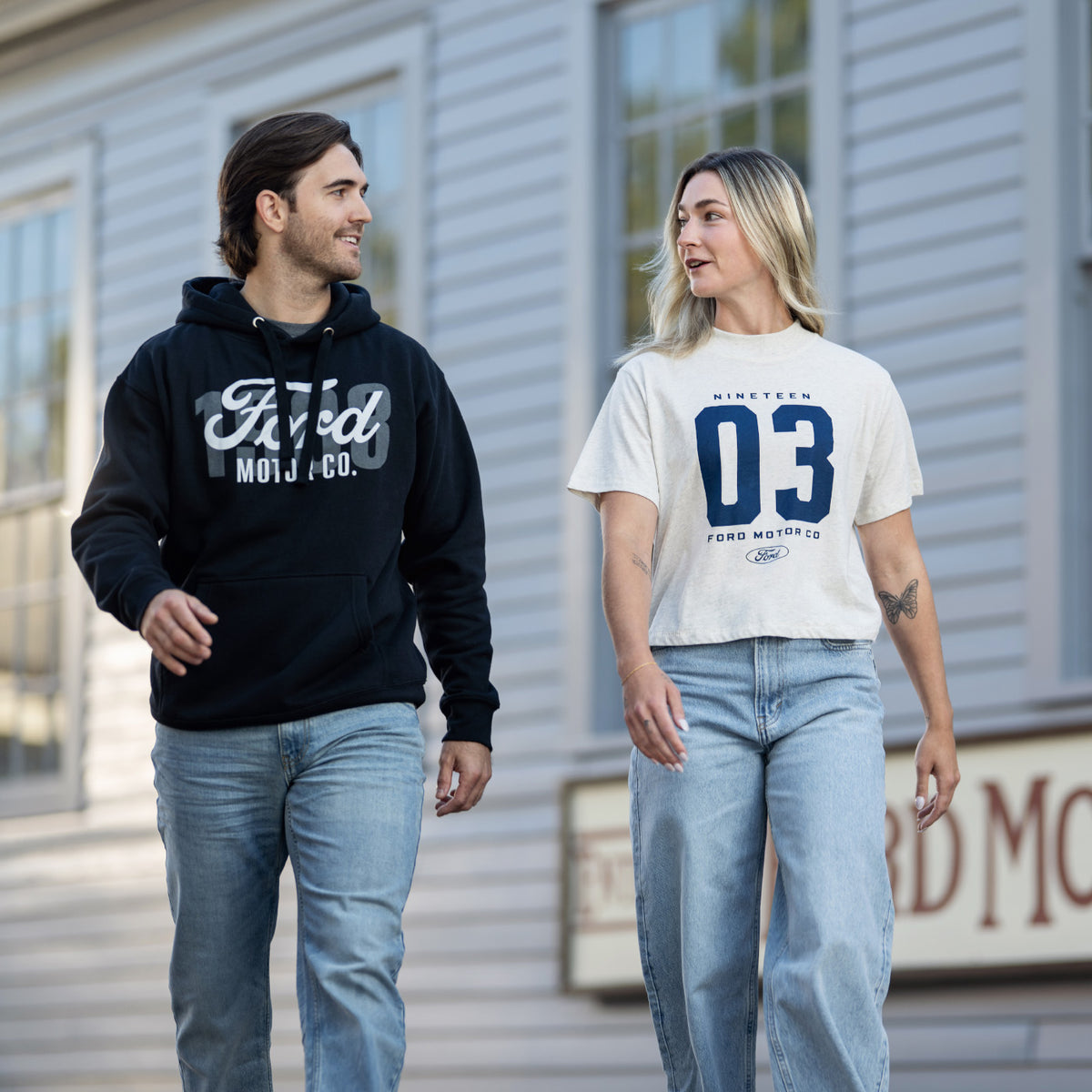 a man and a woman in for motor company clothing and jeans walking outside