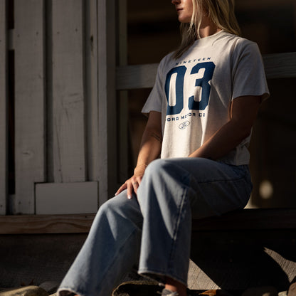 woman in a ford motor co t-shirt sitting outside on a barn step