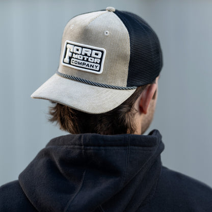 man in a corduroy Ford Motor Company beige hat with black mesh in a black hoodie 