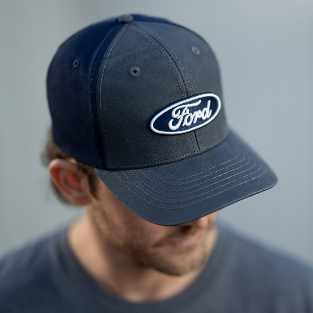 man wearing a gray a navy ford oval hat 
