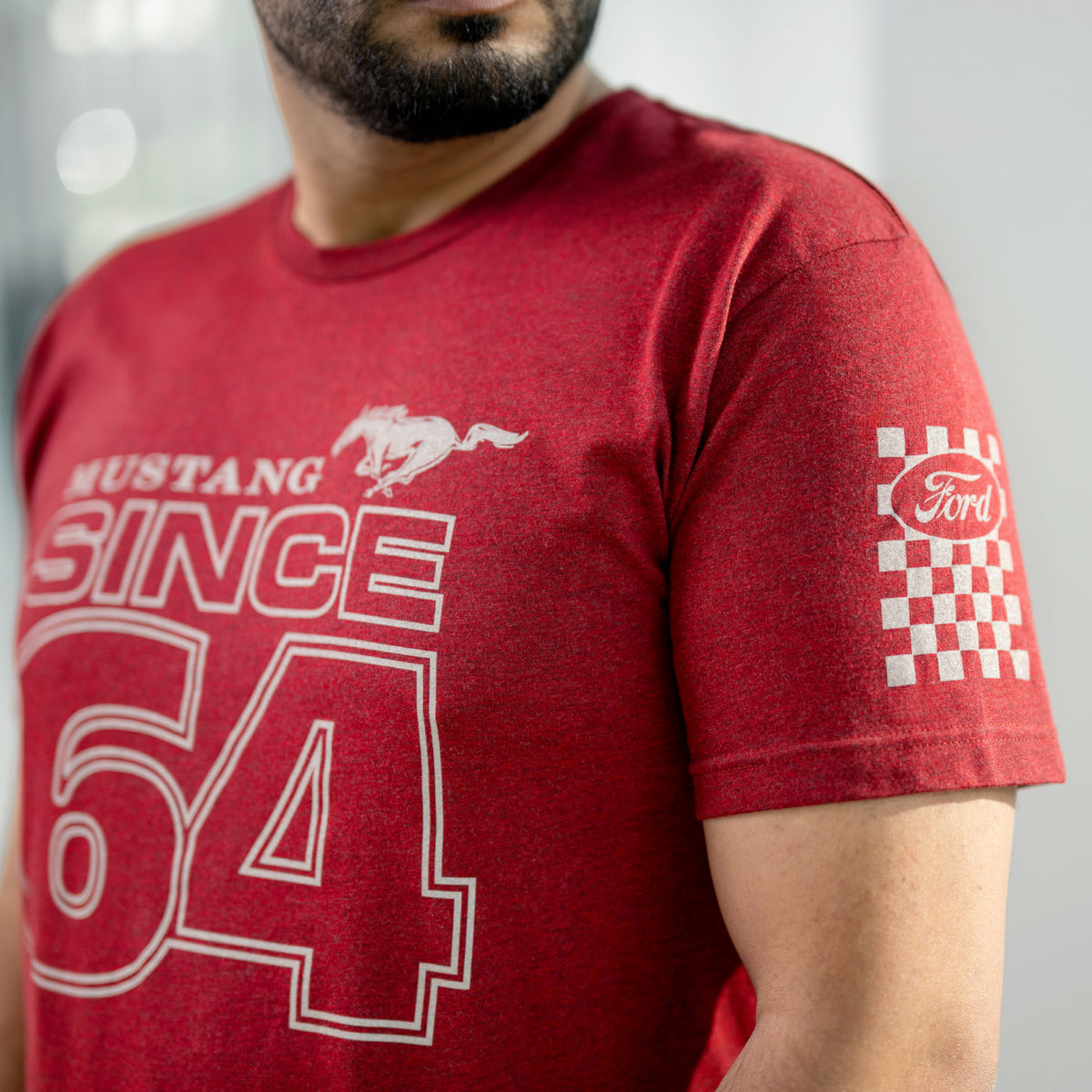man in a red Mustang since 64 t-shirt with a checkered flag on the left shoulder