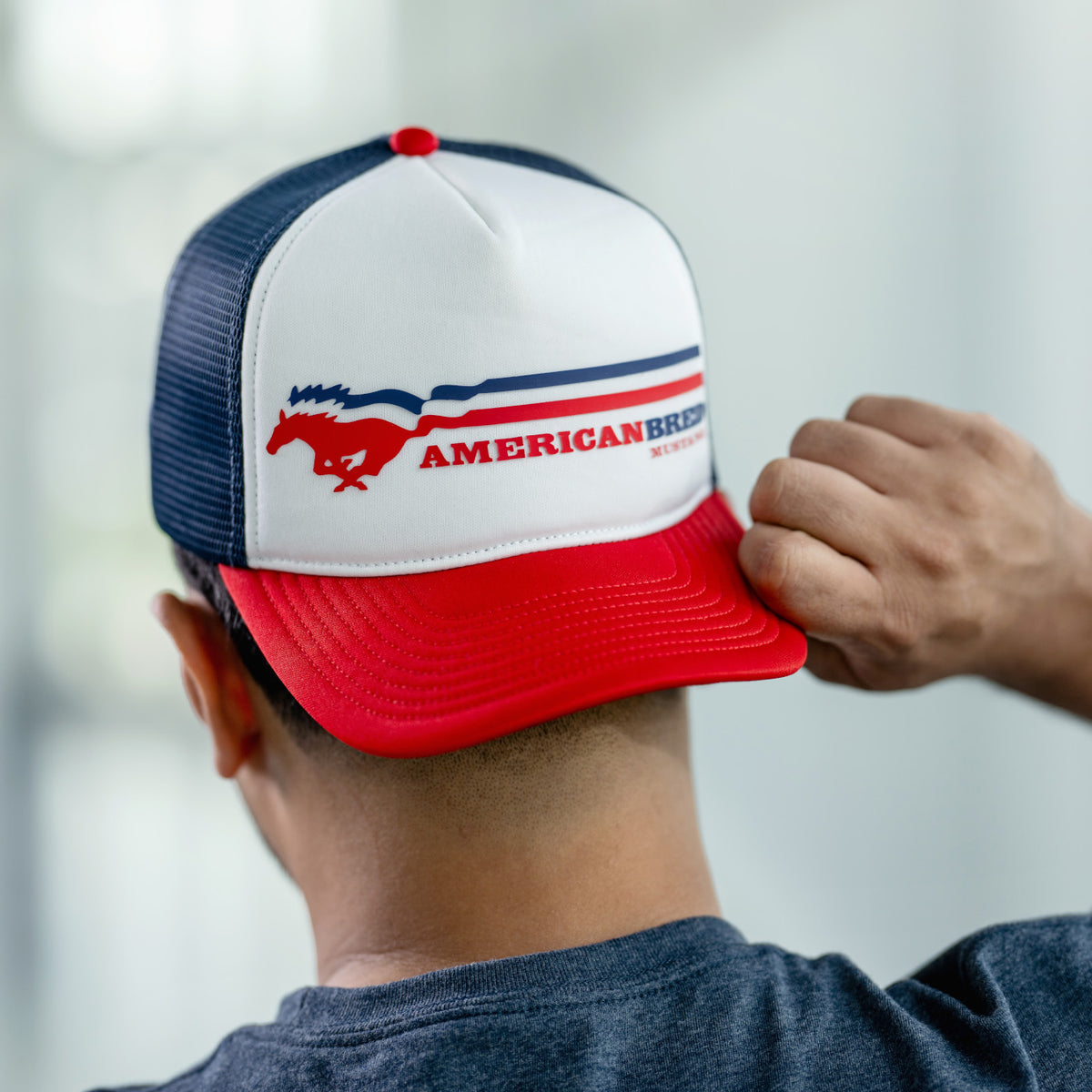 man wearing a RED WHITE and blue American breed Mustang striped hat with a red bill backwards