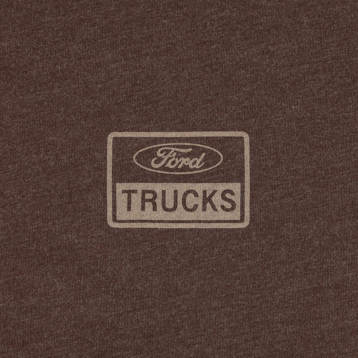 A close-up of a dark brown heathered fabric with a faded beige rectangular Ford Trucks logo printed in the center.