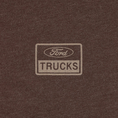 A close-up of a dark brown heathered fabric with a faded beige rectangular Ford Trucks logo printed in the center.