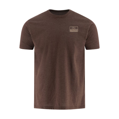 A brown short-sleeve crewneck t-shirt with a small rectangular 'TRUCKS' logo patch on the left chest, displayed on a clean white background.
