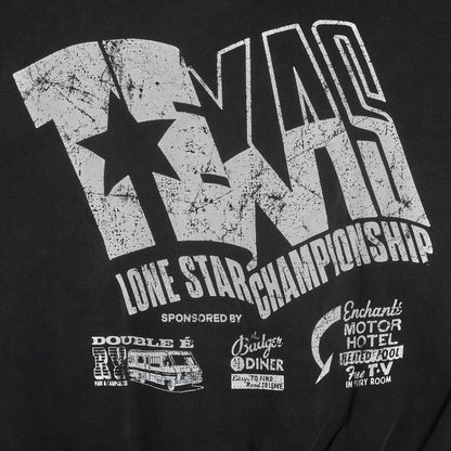 Close-up of a black graphic T-shirt featuring a distressed white 'TNR' logo with a star, the words 'LONE STAR CHAMPIONSHIP,' and smaller sponsor-style prints including 'Double E,' 'Cruiser Diner,' and 'Enchanted Motor Hotel.'.