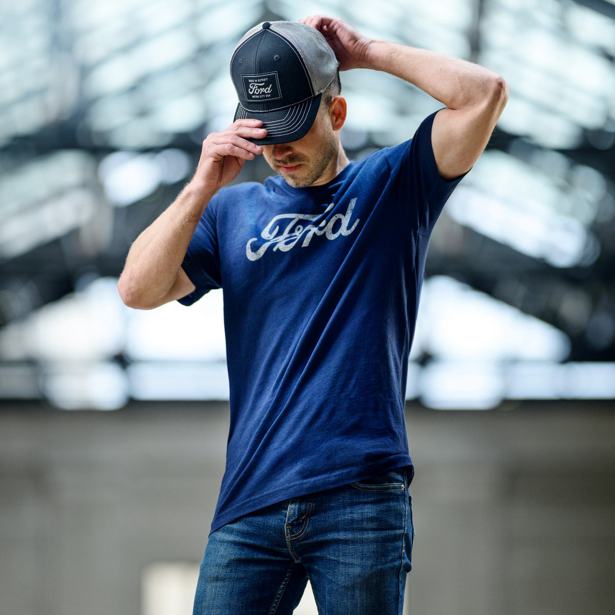 Man wearing a blue Ford t-shirt and black cap with a blurred background