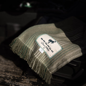 Ford bronco woven green blanket laying on a wood floor