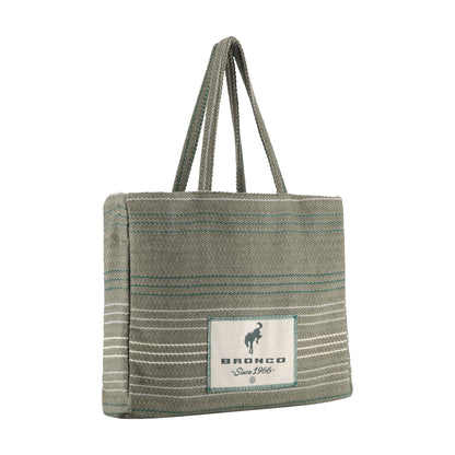 A woven tote bag in a muted sage green color with thin teal and white horizontal stripes, featuring a white rectangular patch on the front with the brand name 'BRONCO' and a horse logo.