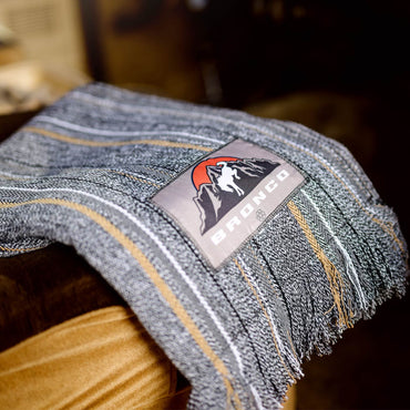 Close-up of a denim fabric with a 'Bronco' brand label on a wooden surface.