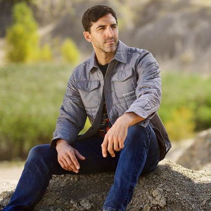 guy looking into the distance sitting on rock wearing gray bronco quilted coat