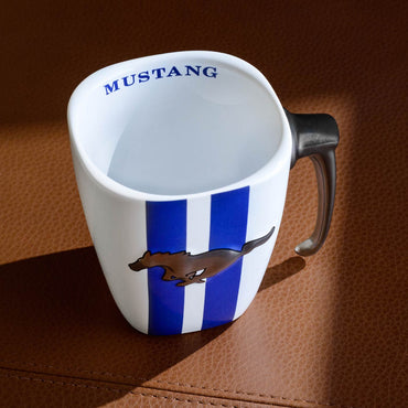 White mug with blue stripes and Mustang logo on a brown textured surface