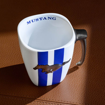 White mug with blue stripes and Mustang logo on a brown textured surface