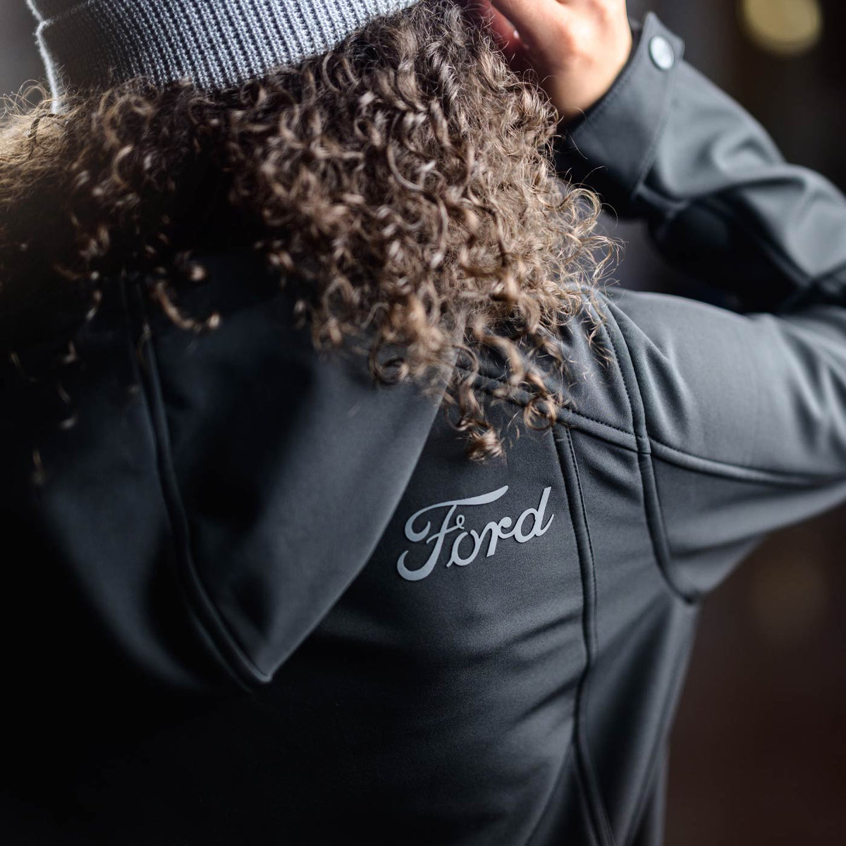 Person wearing a black jacket with 'Ford' logo on the back