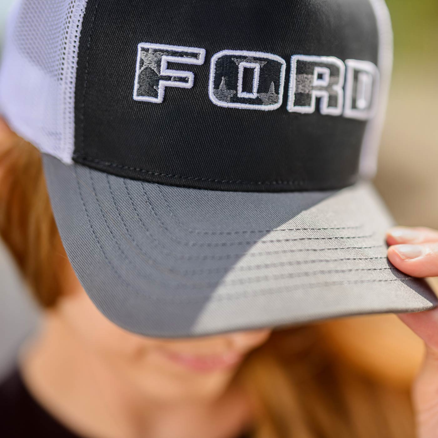 Trucker hat with 'FORD' logo held by a person