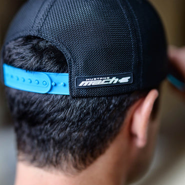 Black cap with blue band and 'Mustang Mach 1' logo worn by a person.