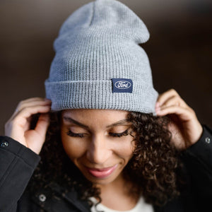 Person wearing a gray beanie with a Ford logo against a dark background