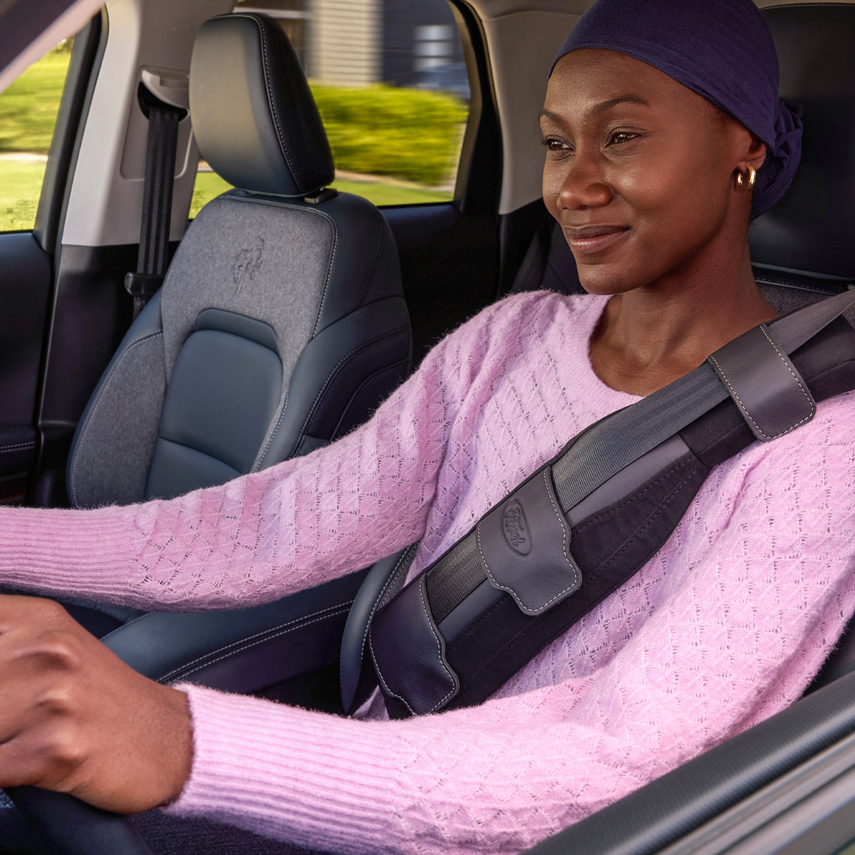 A woman sitting in a vehicle wearing a pink sweater and a SupportBelt™ designed for mastectomy patients.