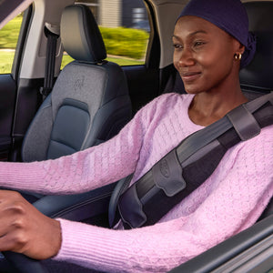 A woman sitting in a vehicle wearing a pink sweater and a SupportBelt™ designed for mastectomy patients.