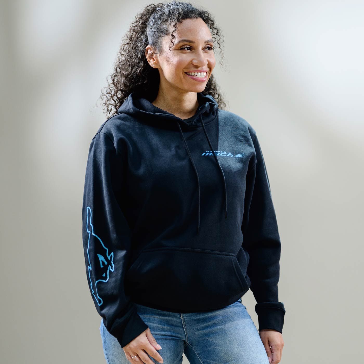 Woman wearing a black hoodie with blue designs on a plain background