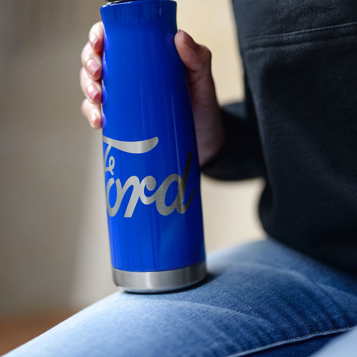 Blue insulated tumbler with 'Ford' branding held by a person wearing jeans.