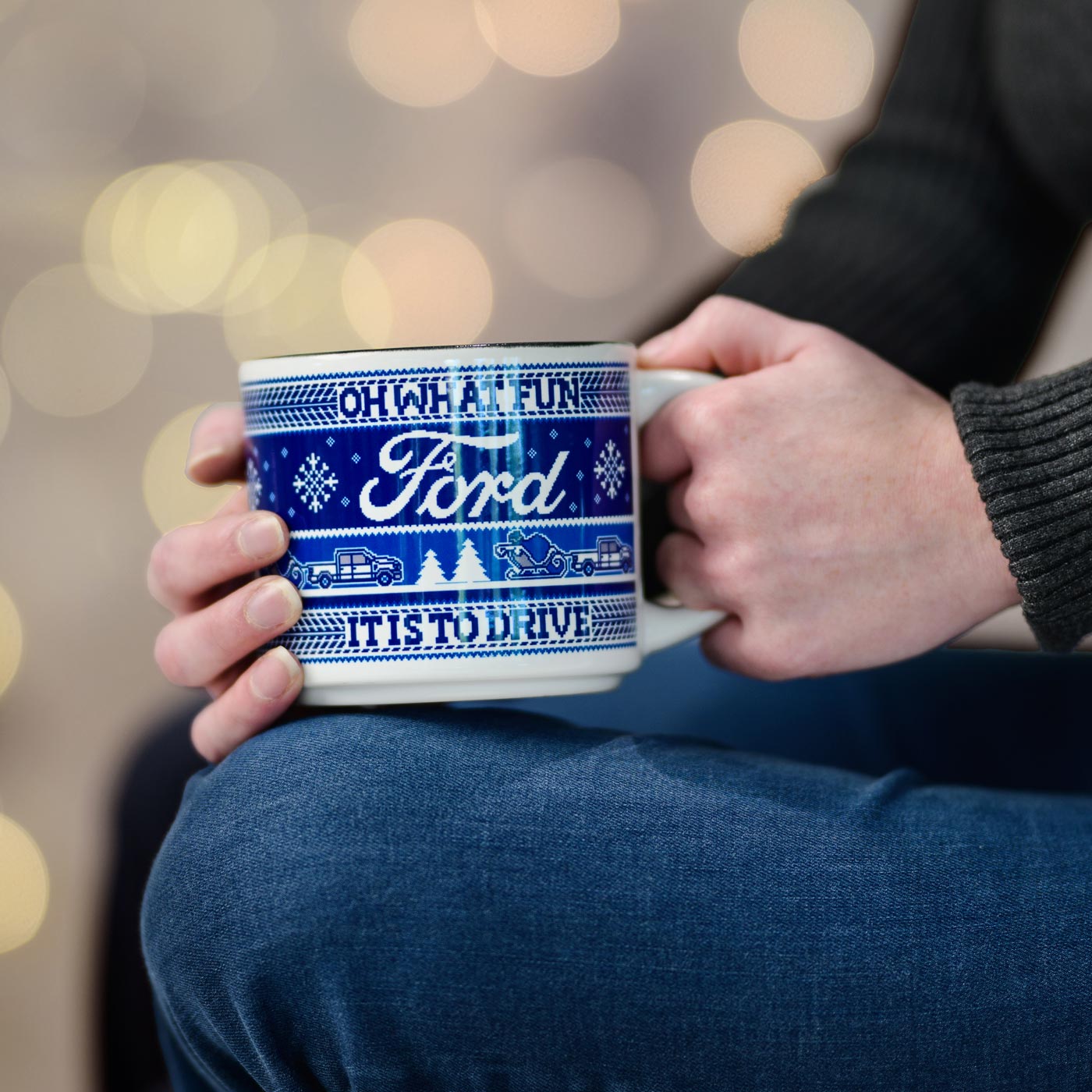person holding a blue and white sweater patterned mug with Oh what fun is is to drive and Ford text